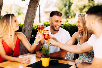 Group of happy friends toasting with beer at the summer bar