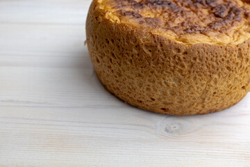 Freshly baked bread on white table, side view. A round bread lies on the right side of surface for publication, poster, calendar, post, wallpaper, card, cover, website, space for your design or text