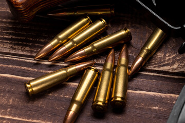 Bullets and Kalashnikov assault rifle on wooden background. Cartridges 7.62 caliber for ak 47 closeup. Selective focus