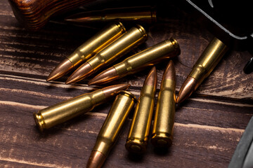 Fototapeta premium Bullets and Kalashnikov assault rifle on wooden background. Cartridges 7.62 caliber for ak 47 closeup. Selective focus