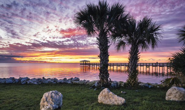 Colorful sunrise over the Rotary Riverfront Park with palms in Titusville, Florida