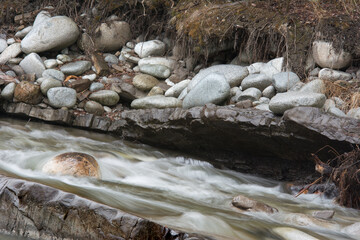 Running water in a  mountain stream with rocks and round stones