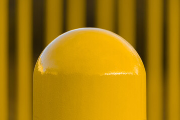Closeup shot of a yellow pole or bollard on the street on a blurred background