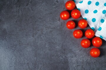 Ripe cherry tomatoes on a gray marble table surface with a cloth napkin. Flat lay, copy space