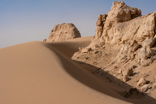 Low angle shot of sand dunes and yardangs on a desert