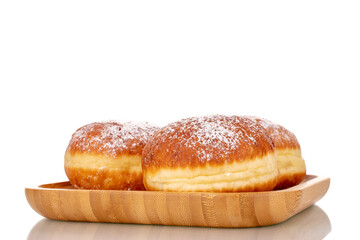Three sweet donuts stuffed with jam on a bamboo tray, close-up, isolated on a white background.