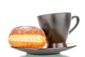One sweet donut filled with jam with a black ceramic cup on a saucer, close-up, isolated on a white background.