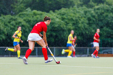 Young girl field hockey player running with the ball in attack 
