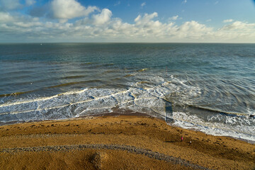 Beautiful scene of windy waves in the blue sea with a cloudy blue sky on the horizon near the beach