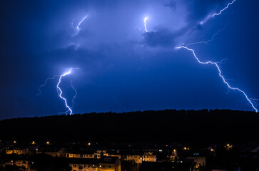Lightning streaks against a blue night sky over the city of Stuttgart, Germany