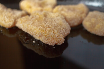 Chicken nuggets in breadcrumbs in a black cast-iron pan for baking