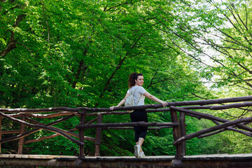 Fototapeta premium a female traveler walks through a green forest on a hike