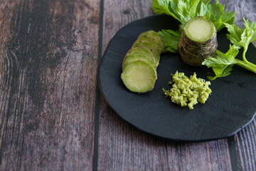 Plate of Japanese horseradish or wasabi on a wooden table - obrazy, fototapety, plakaty