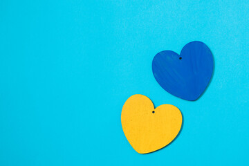 Two blue yellow wooden hearts on a blue background. Hearts in a colors of the flag of Ukraine. Ending the war in Ukraine concept.