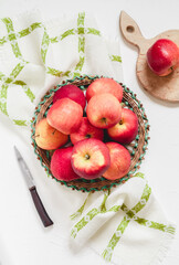Fresh juicy red apples in a wicker basket on a linen napkin. Top view.