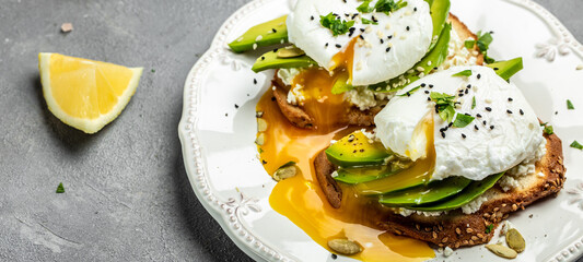 Healthy breakfast. Whole wheat toasted bread with avocado, poached egg, soft cheese and pumpkin seeds. Delicious snack, Clean eating, dieting, vegan food concept. Long banner format. top view