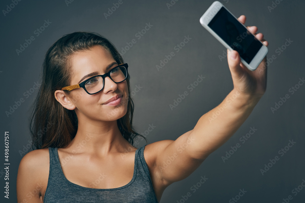 Sticker Your smile is the best filter you have. Studio shot of an attractive young woman taking a selfie against a grey background.