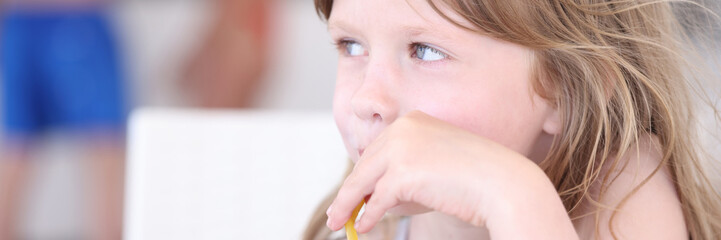 Little girl drinking nonalcoholic cocktail from straw at beach bar