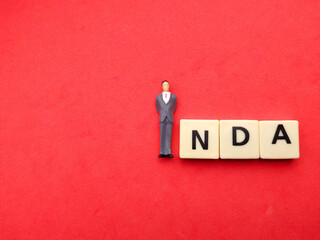 Miniature of a man with the word NDA on a red background with copy space