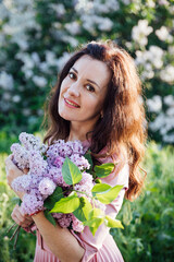 Naklejka premium beautiful woman with a bouquet of lilac flowers in spring