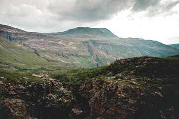Beautiful landacape view of large green rocky hills against light cloudy sky