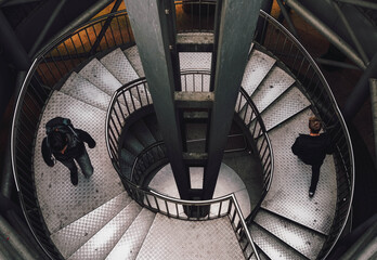 Top-view of people walking down the spiral stairs - Powered by Adobe