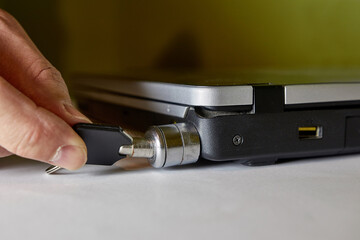The man locks the laptop with a special anti-theft lock.