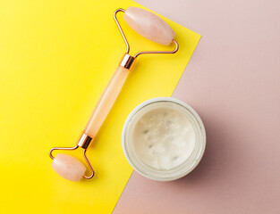 Set for personal morning beauty routine. Facial roller for massage and open jar with cream. Female spa, beauty treatments. Flat lay, copy space, creative layout