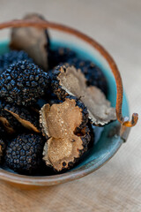 Truffles in a small copper bucket. Sliced mushrooms. Black raw champignons on the surface. Top view. Dark background. Shallow depth of field.The artistic intend and the filters.