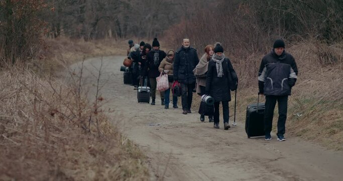 War Immigrants With Luggage Walking On Road During Snowfall.