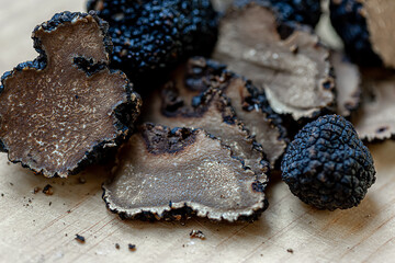 Black truffles on the surface.Mushrooms. Raw champignons on a beige burlap. Top view. Dark background. Shallow depth of field.The artistic intend and the filters.