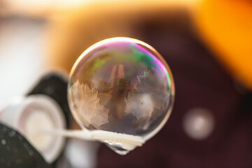 a girl holds a soap bubble with beautiful frost patterns in the rays of the sun in winter