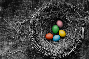 Five colored  Easter chicken eggs in a basket with straw, rustic style, table, top view, toned black