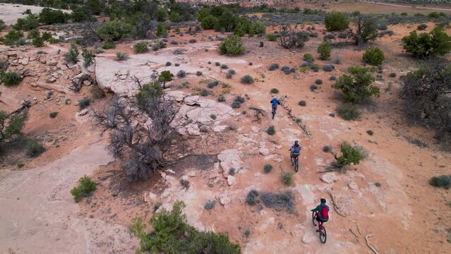 Bikers riding mountain bikes in unearthly landscape in the Utah mountains on a dirt road. Active lifestyle. Top aerial view. Drone footage. 