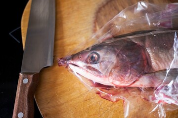 cut into pieces frozen salmon or salmon fish lies on a wooden board with a knife
