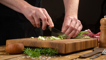 Cutting green onions with a knife on a cutting board