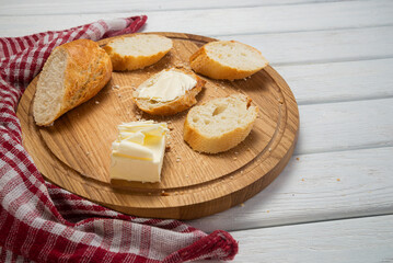 Fresh french baguette with butter on dark background