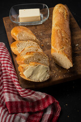 Fresh french baguette with butter on dark background