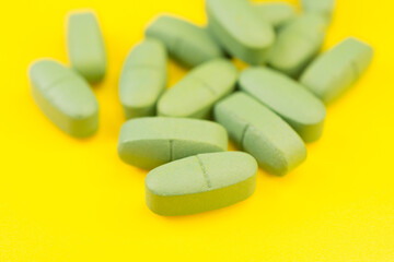 Fototapeta na wymiar Green cold pills on a yellow