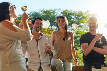Enjoying some wine in the sunshine. Shot of a group of happy young friends hanging out at a backyard dinner party.