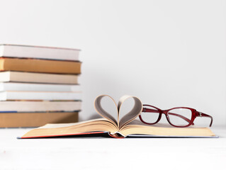 A stack of books on a white background. Glasses on the top book. World book day concept.
