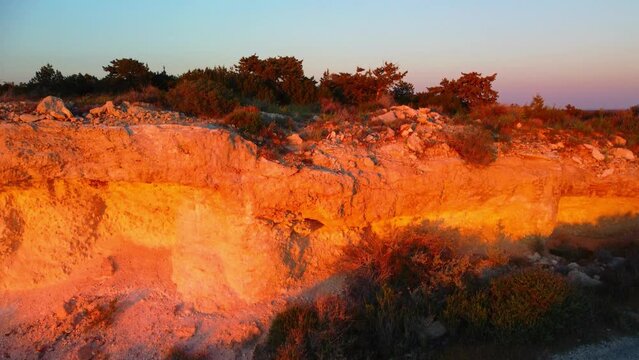 Drone flight over the Mediterranean coast over the forest and rocks in the rays of sunset in Cyprus. Zapallo bay.