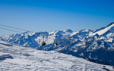 Beautiful winter landscape at Madonna di Campiglio Ski Resort, located at the area of the Brenta Dolomites in Italy, Europe. Chairlift with skiers and snowboarders going up to the peak.