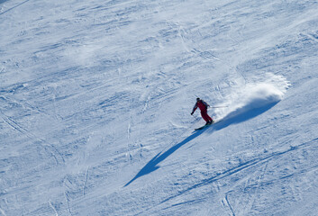 Dynamic photo of skier downhill in fresh snow on a sunny winter day at the Madonna di Campiglio Ski Resort in Italy, Europe.