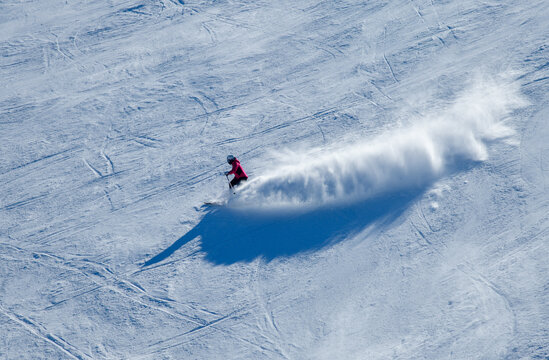 Dynamic photo of skier downhill in fresh snow on a sunny winter day at the Madonna di Campiglio Ski Resort in Italy, Europe.