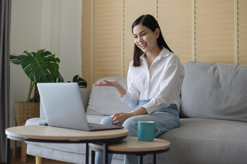 Beautiful young woman making video conference call via computer at home , business technology concept