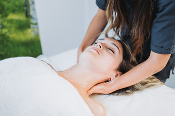 Female therapist making a neck massage to a face up female patient. Wellness center spa. Skin care.