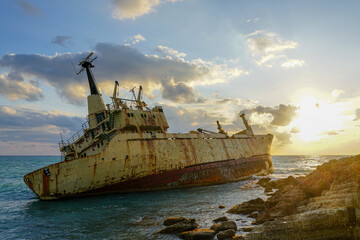 Fototapeta na wymiar a large rusty shipwreck on a rocky coast against a beautiful sunset background