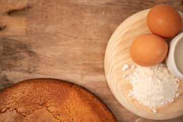 Homemade yogurt sponge cake served with fresh eggs, flour and oat milk on a wooden board on a wooden base