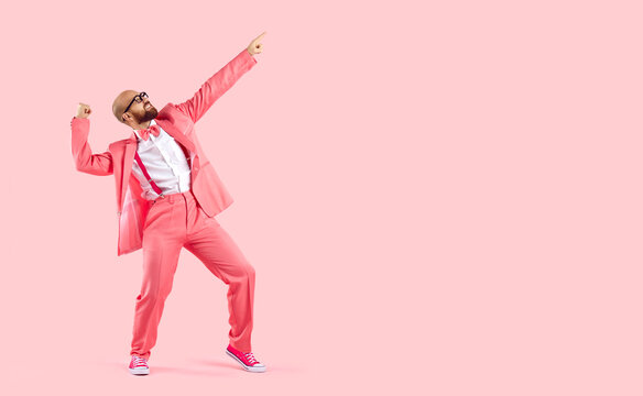 Cheerful successful man dancing funny making movements winner isolated on pink background. Funny man in pink formal suit celebrates his success having fun at copy space. Full length. Banner.